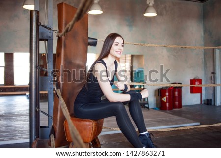 Girl athlete preparing for training, young woman in sportswear in the Boxing ring. Sitting on a chair
