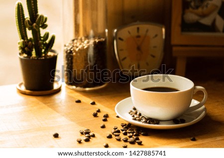 Coffee cups and roasted coffee beans at the middle level on table by the window