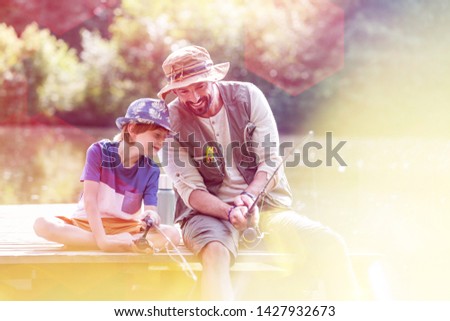 Happy father and son fishing in lake while sitting on pier