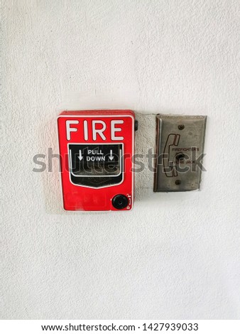 Red​ fire alarm switch and​ Fire​ fighters​ Phone​ jack on​ the​ interior​ cement​ wall, safe​ty​ concept.