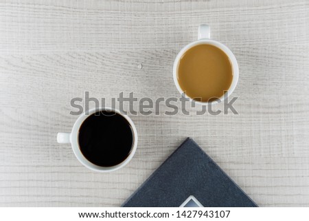 coffee book concept. Black coffee and coffee milk in a cup with a hardcover book on a wooden table