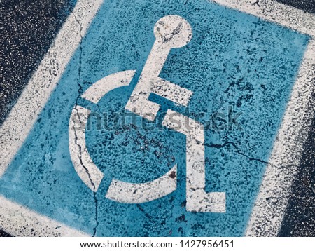close up blue handicap sign on parking lot