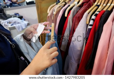 Unrecognizable woman looking at price tag during choosing clothes to buy