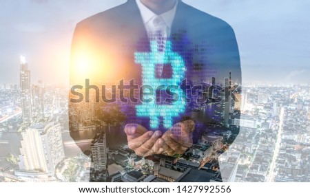 Double exposure image of Businessman hand holding bitcoin digital hologram and internet of things on city background.making money with bitcoin - Business man creating bitcoins with his hand.
