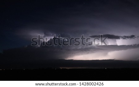 A severe thunderstorm is illuminated by lightning as stars shine overhead in western Nebraska on a summer night. 