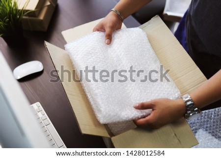 hand of business man holding Bubble Wrap or Bubble sheet for Wrapping near parcel box on black desk in home office ,Work from Home