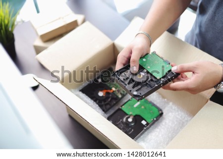 hand of business man holding Harddisk for PC and Bubble Wrap or Bubble sheet for Wrapping near parcel box on black desk in home office .selective focus