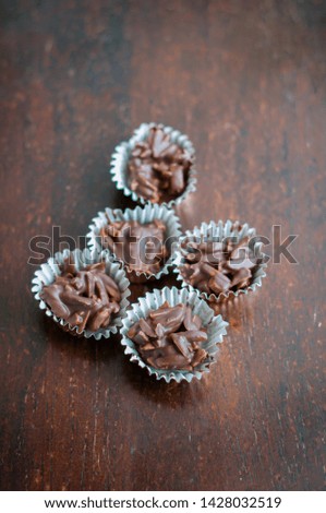 Chocolate Covered Almonds in golden paper cups on a wooden background.
