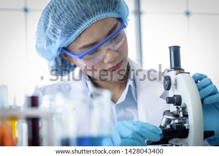 Asian yound student scientist researching with a microscope in a laboratory.