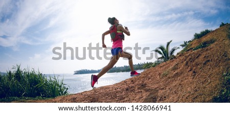 Woman trail runner running on seaside hills Royalty-Free Stock Photo #1428066941