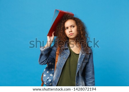 Young african american girl teen student in denim clothes backpack hold folder isolated on blue background studio portrait. Education in high school university college concept. Mock up copy space