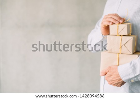 Online gift shop. Delivery service. Cropped shot of business man holding paper wrapped boxes. Gray wall background. Copy space.