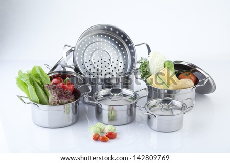 Set of stainless pots with lids and vegetable Royalty-Free Stock Photo #142809769