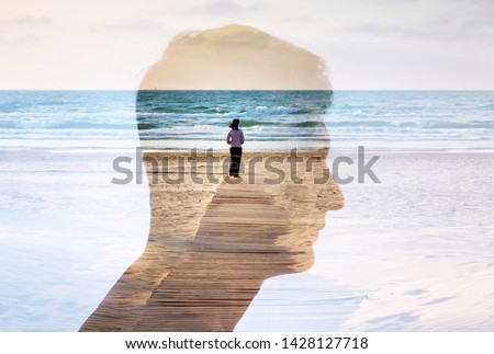 Silhouette of a male head and a lonely girl on a background of sunset and the sea. A good concept background on the theme of love, romance of the relationship between a man and a woman.