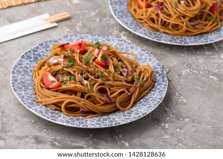 Udon stir fry noodles with vegetables in plate with chopsticks