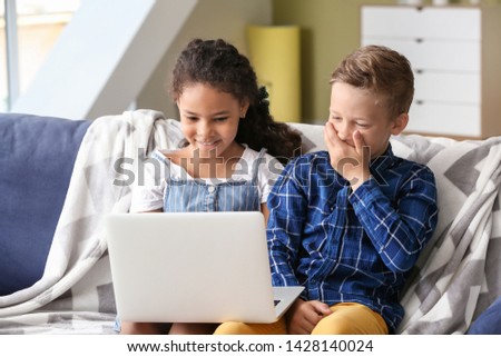 Happy adopted children with laptop watching cartoons in their new home