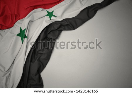 waving colorful national flag of syria on a gray background.