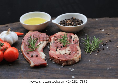 Raw beef steak with rosemary and vegetables on wooden dark background, food meat or barbecue