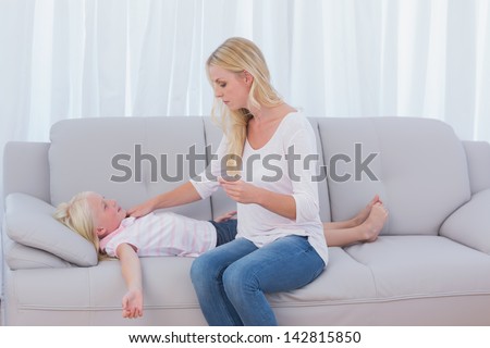 Mother checking the temperature of her daughter in the living room