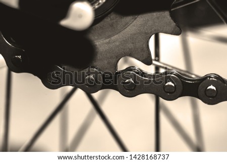Dark metallic chain of a Bicycle filmed in close up. small details are visible. The background is blurred.