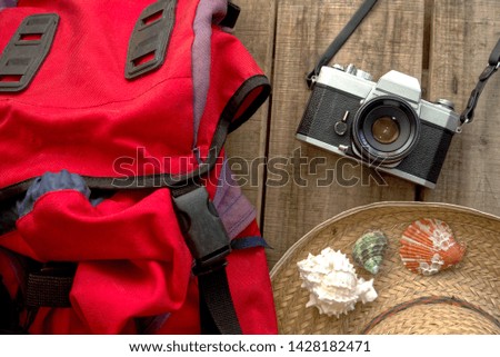Topview camera and travel shoulder bag and hat decorate with sea shell on wood background,summer concept                    