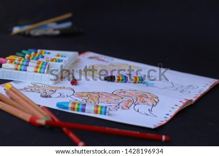 Children's coloring books and crayons over black table.