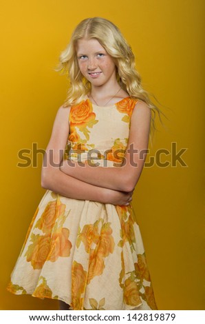 Beautiful blonde girl on a yellow background. In a beautiful flowered dress, happy with a sweet smile