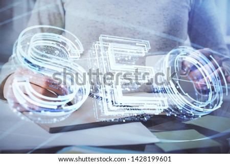 Multi exposure of woman's hands making notes with SEO icon. Concept of Search engine optimization