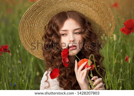 girl in a poppy field in a straw hat