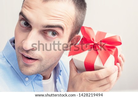An attractive man received a gift. The man wondering what he was given. Portrait, close up, toned