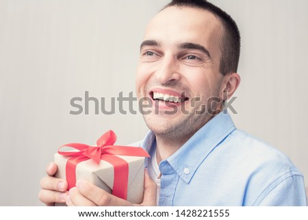 An attractive man received a gift for his birthday. The man is happy and laughs joyfully. Portrait, close up, toned