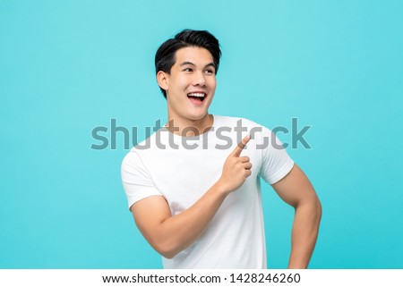 Handsome healthy young Asian man smiling with his finger pointing isolated on light blue studio background Royalty-Free Stock Photo #1428246260