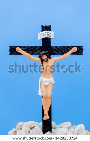 Cross Jesus Christ. Plaster figure on a blue background