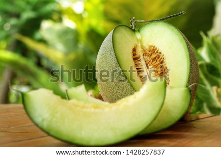 Sliced of Honeydew melons,honey melon or cantaloupe (Cucumis melo L.) on wooden table with blurred garden background.Favorite fruit in summer.Fruits or healthcare concept.Selective focus. Royalty-Free Stock Photo #1428257837