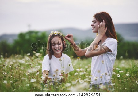 Mom and daughter collect chamomile flowers leisure leisure nature games