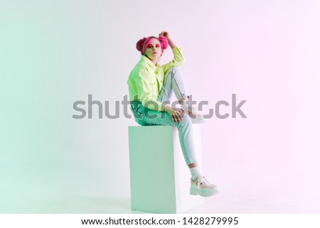 woman sitting on a cube with pink hair