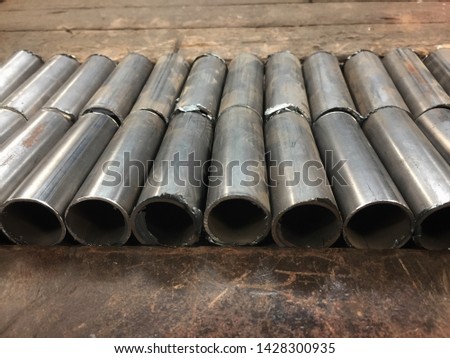 Iron tubes used in construction industry on wood background.