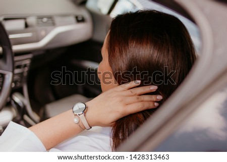 Beautiful successful elegant brunette young woman in watch and bracelet on hand driving passenger car