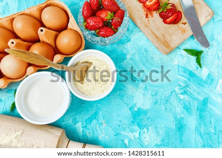 Bakery background. Recipe for strawberry pie. Raw ingredients for cooking strawberry pie or cake on blue background. Top view, flat lay. Copy space. 