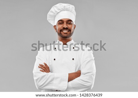 cooking, profession and people concept - happy male indian chef in toque over grey background Royalty-Free Stock Photo #1428376439