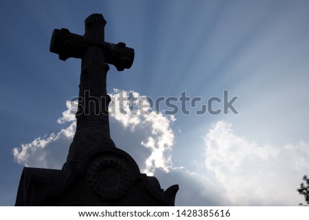 Sunrays: atmospheric coditions highlight the rays of the sun bursting from behind Cumulus cloud in the background, and gravestones in the foreground