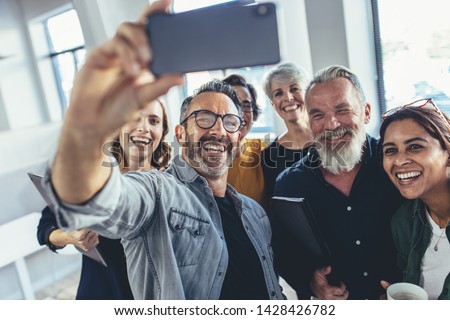 Successful business team taking selfie together. Multiracial group of people taking selfie at office.