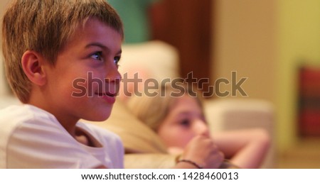 Young boy in front of tv screen watching movie with real life authentic reactions smiling to content