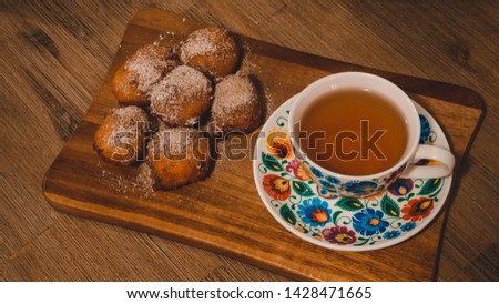 Exposition of donuts with cup of tea, cinnamon and sugar on black table, very tasty cakes for any celebration.