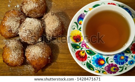 Exposition of donuts with cup of tea, cinnamon and sugar on black table, very tasty cakes for any celebration.
