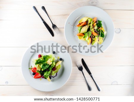 Fruit salad mixed with fresh fruits. Top view. two plates with summer fresh fruit salad on a wooden table