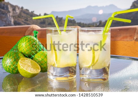 Lime. Fresh Juice from lime. Two glasses of Juice with just squeezed out of ripe citrus fruits along with a pack of lime and half a lime against a beautiful landscape 