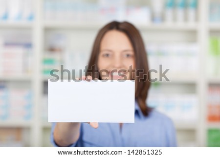 Portrait of female pharmacist holding blank placard in pharmacy