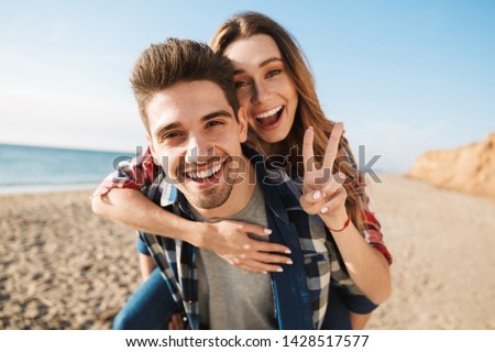Photo of happy young loving couple outside in free alternative vacation camping showing peace gesture.