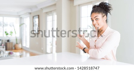 Wide angle of beautiful african american woman with afro hair Inviting to enter smiling natural with open hand
